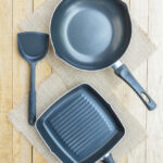 Non-stick frying pan and grill pan with spatula on wooden surface for healthy cooking