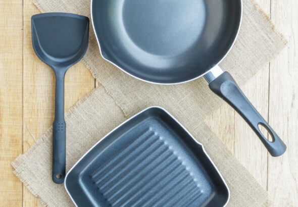 Non-stick frying pan and grill pan with spatula on wooden surface for healthy cooking