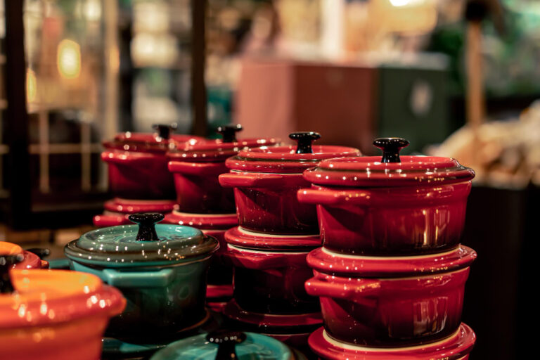 Colorful ceramic cookware set with stacked pots and pans in a kitchen store display