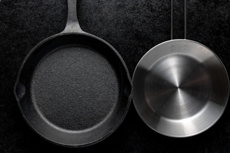 Cast iron skillet and stainless steel pan side by side on dark background comparison