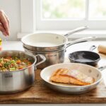 Nickel-free stainless steel cookware set with ceramic-coated interiors and a cast iron skillet, used to prepare salmon and vegetable soup